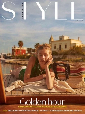 Magazine cover featuring a woman reclining on a boat, showcasing Loewe tote bag, set against a coastal backdrop with clear blue sky.