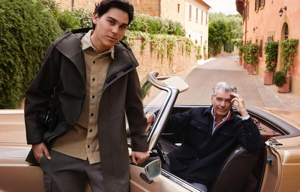 Two men posing with a tan convertible in Italy: one standing in a dark green jacket, and the other seated in the driver's seat.