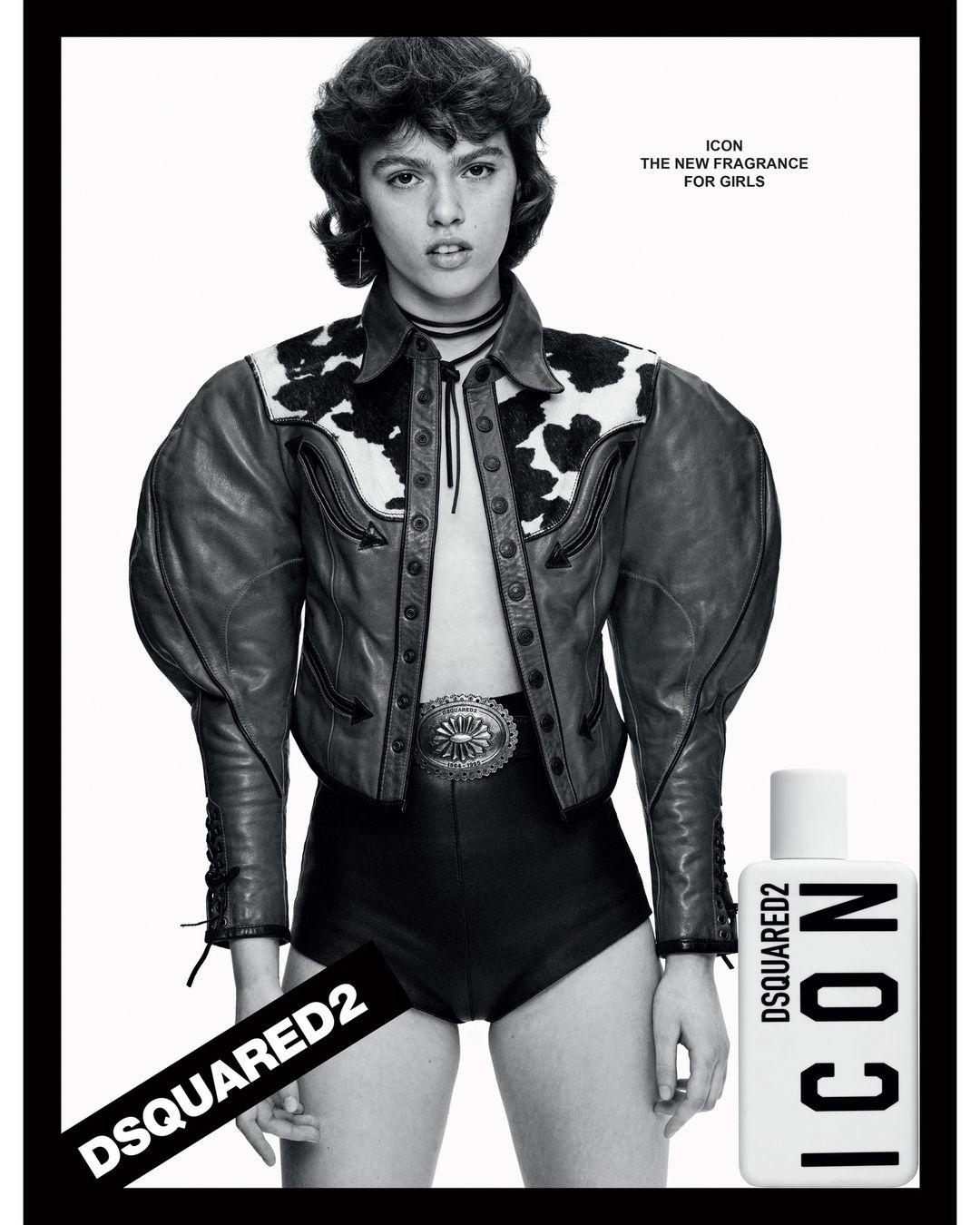 A young woman poses in a black and white fashion shot, wearing a leather jacket and shorts, advertising a perfume.
