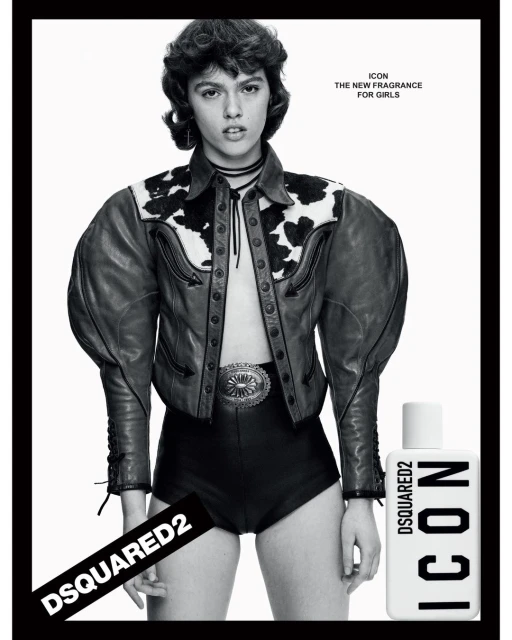 A young woman poses in a black and white fashion shot, wearing a leather jacket and shorts, advertising a perfume.