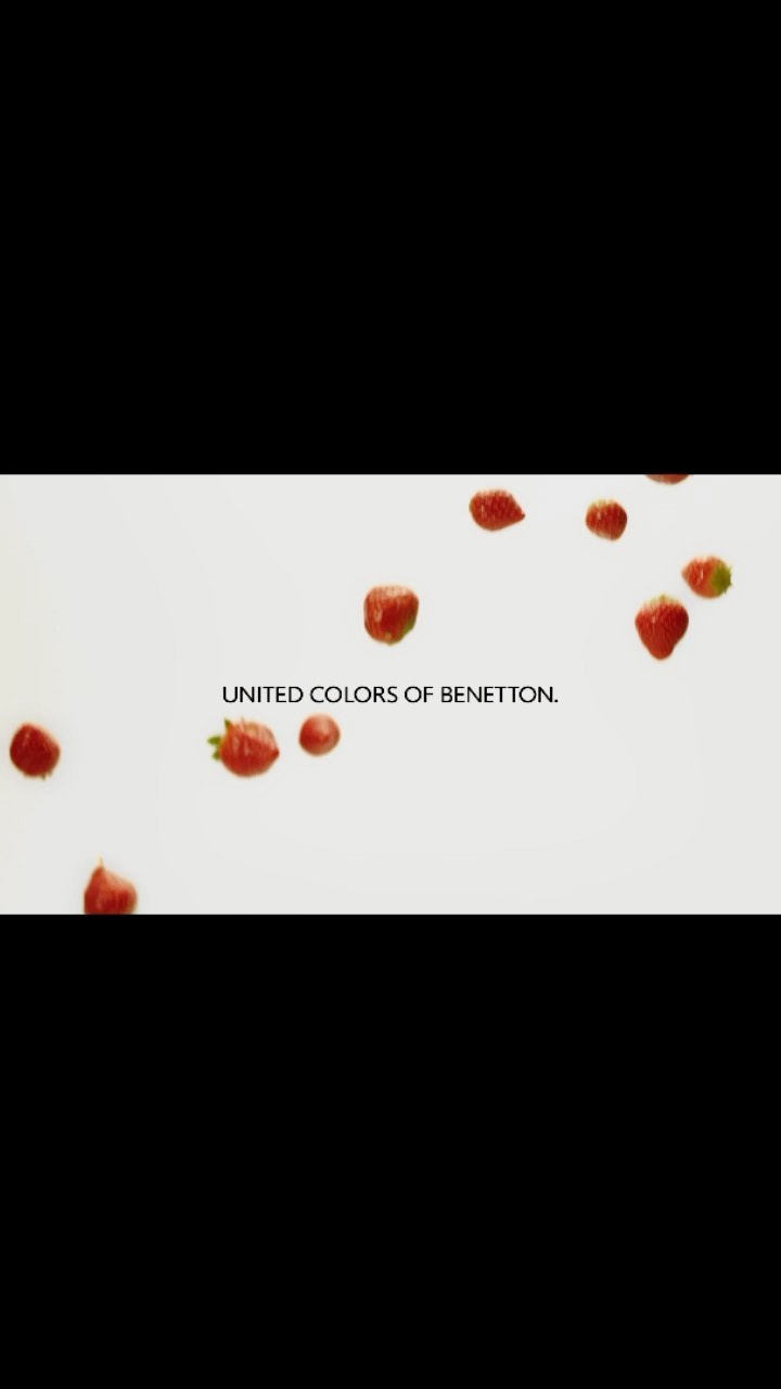 Scattered fresh strawberries and the UNITED COLORS OF BENETTON text logo set against a light background, creating a vibrant and playful food scene.