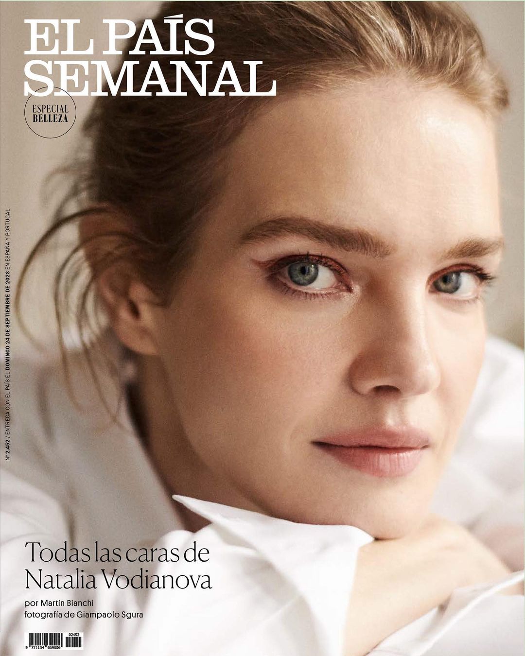Close-up portrait of Natalia Vodianova with winged eyeliner wearing a white collared shirt against a neutral background