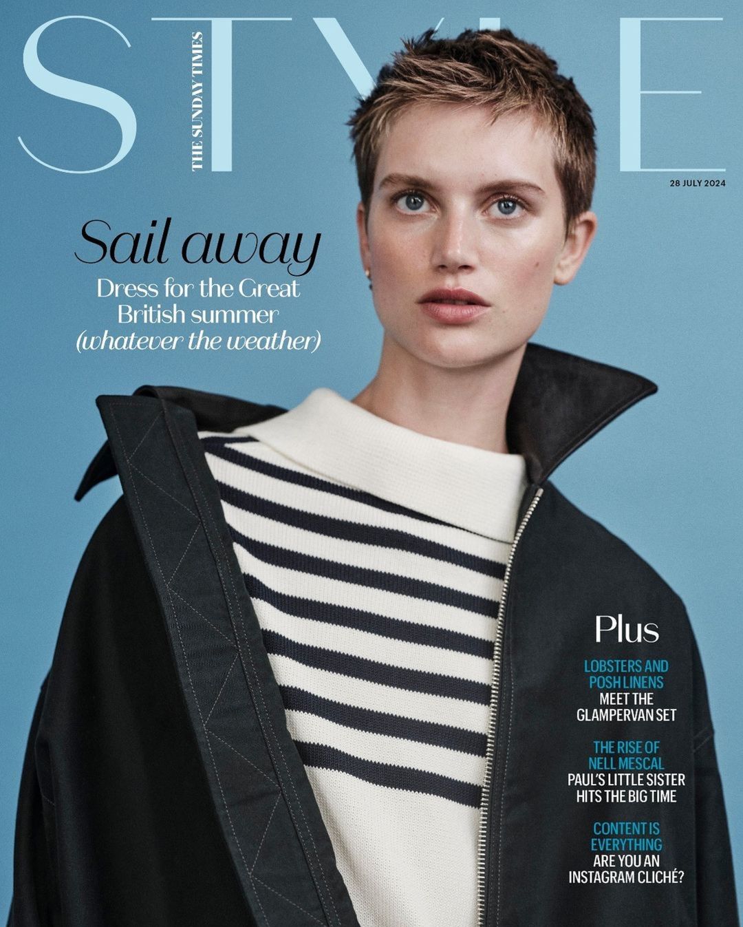 Model with short brown hair wearing a striped sweater and black jacket against a blue background