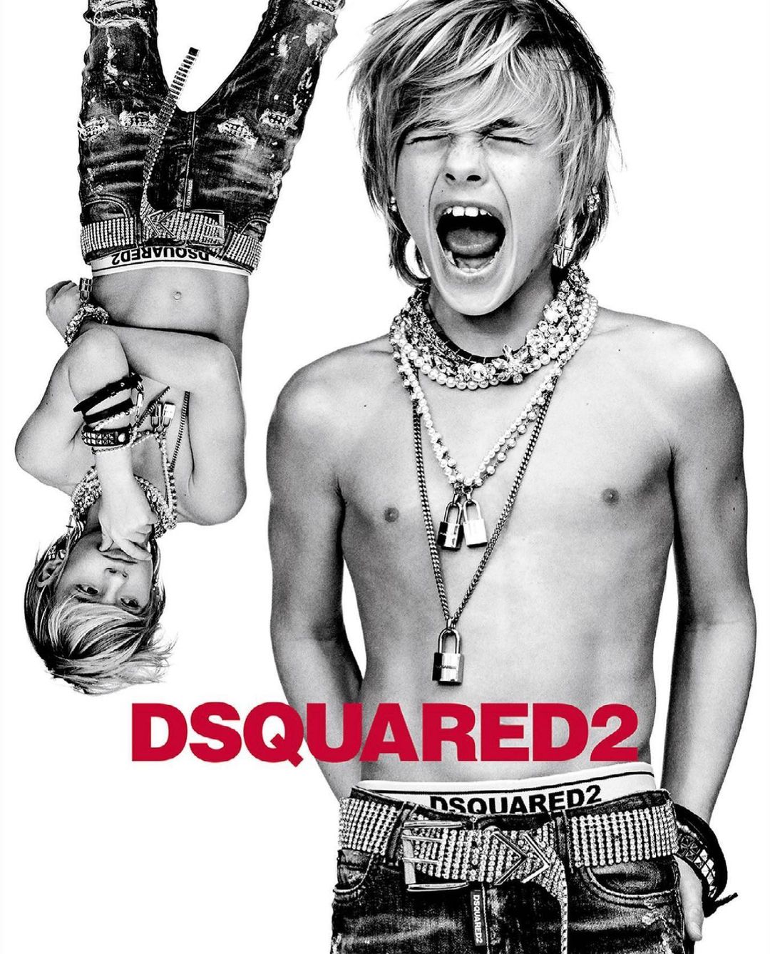 Black-and-white studio portrait of a screaming shirtless boy with blonde hair, jeans, jewelry, and the DSQUARED2 logo visible.