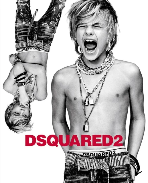 Black-and-white studio portrait of a screaming shirtless boy with blonde hair, jeans, jewelry, and the DSQUARED2 logo visible.