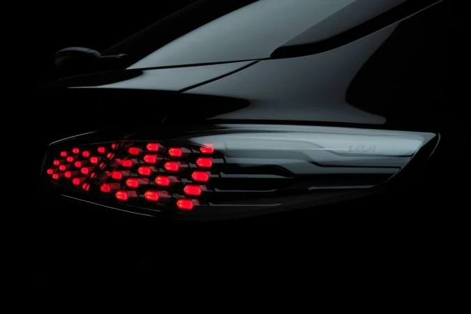 Close-up studio shot of the rear taillight assembly of a sleek, dark-colored car with red LED lights against a black backdrop.
