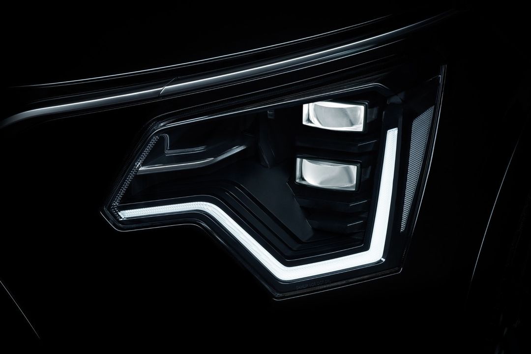 Close-up of an automotive LED headlight with a modern design featuring black housing and geometric patterns of bright white light.