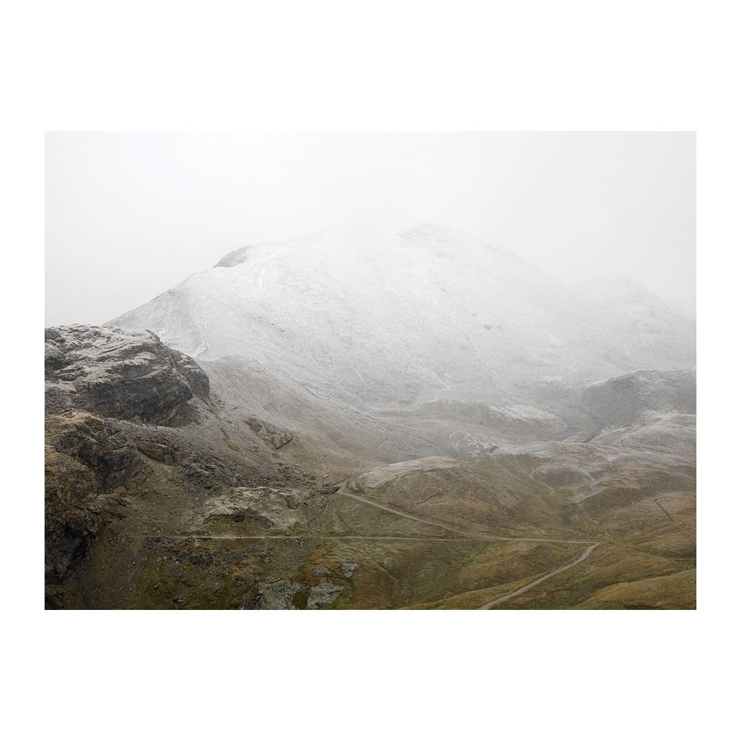 Scenic view of a mountain range covered in snow and fog, creating a serene and tranquil landscape on a cloudy day.