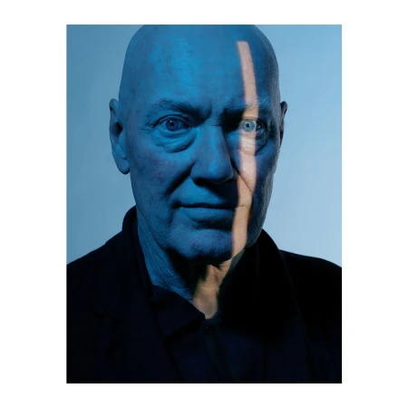 Close-up portrait of an elderly bald man with a vertical beam of light cutting across his face, photographed by Gian Paul Lozza.