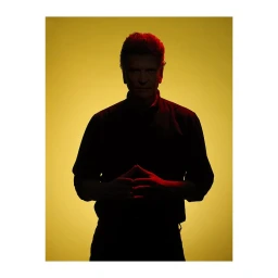 Portrait of a man in silhouette against a yellow background with red rim lighting by Gian Paul Lozza