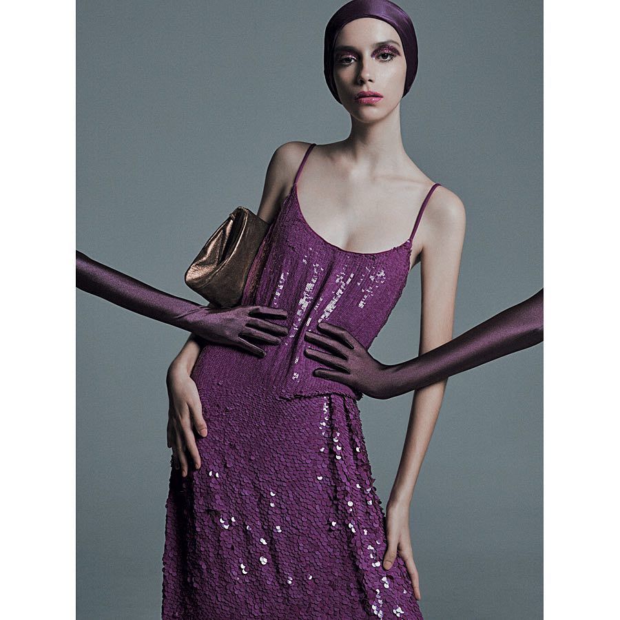 A fashion portrait features a model in a purple sequin dress and matching head covering with gloved arms framing her body.