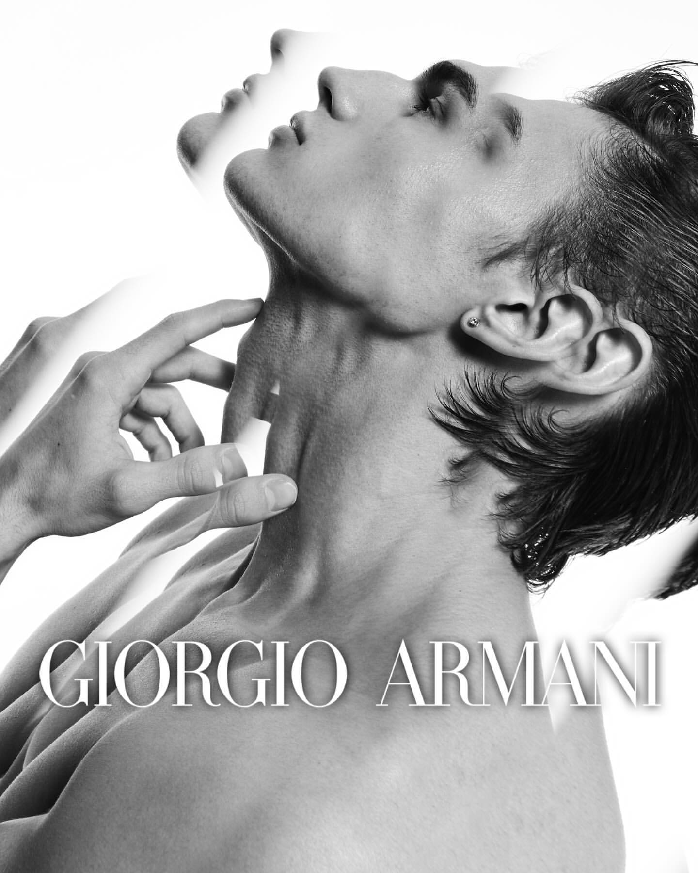 Black and white fashion portrait of a bare-chested adult male model with a translucent double exposure effect and Giorgio Armani branding.