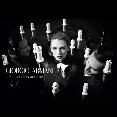 Black and white studio shot with a female model and two male models surrounded by chess pieces, promoting Giorgio Armani's Made to Measure.