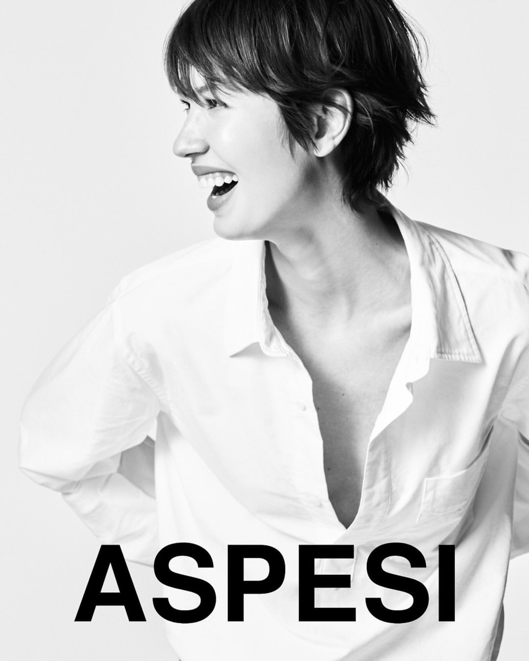 Black and white portrait of an adult woman with a short hairstyle smiling in a white button-down shirt against a white background.