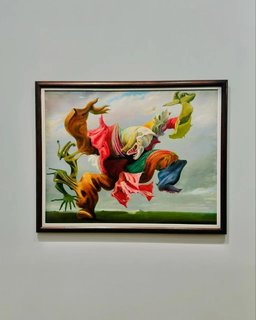A surrealist oil painting depicts a figure formed from intertwined organic shapes and draped in colorful fabrics against a neutral backdrop.