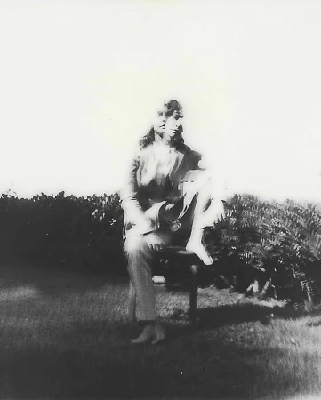Portrait of a seated person outdoors captured in a grainy black and white aesthetic with multiple exposures.