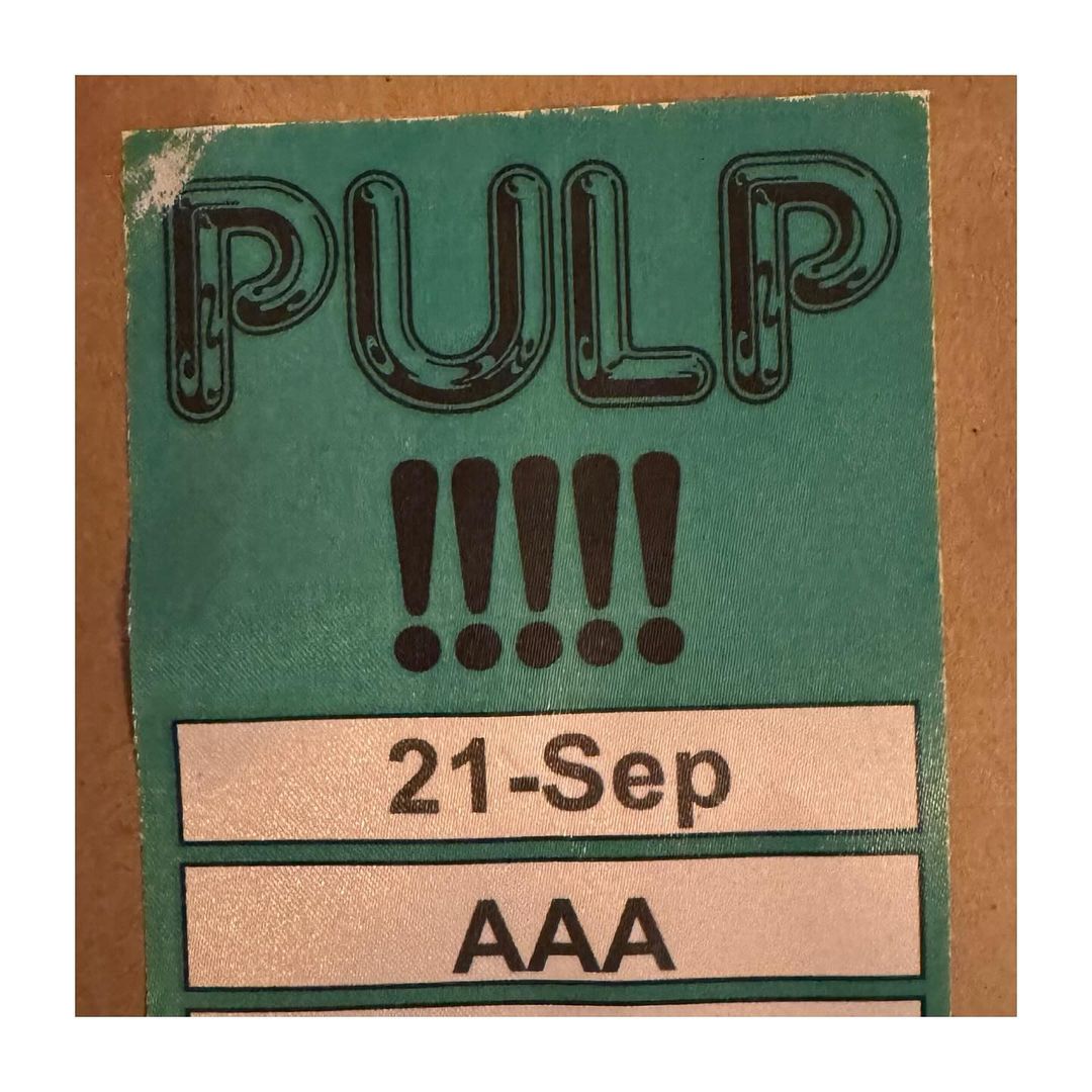 Pulp ticket graphic with bold text and exclamation points on a light teal background, featuring the date September 21 and the code AAA.