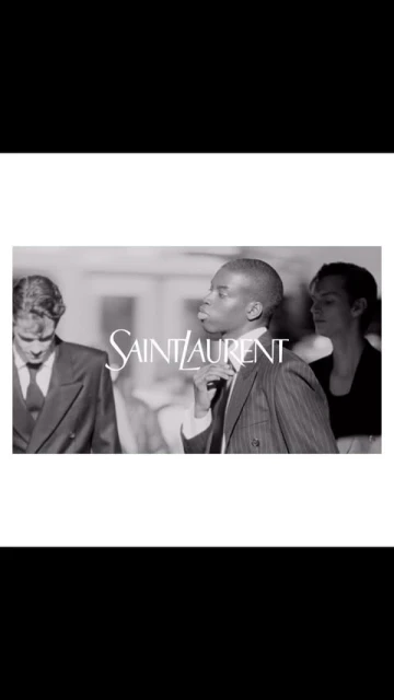 Black and white fashion-editorial shot featuring three people and the Saint Laurent logo in the foreground. Classic formalwear.