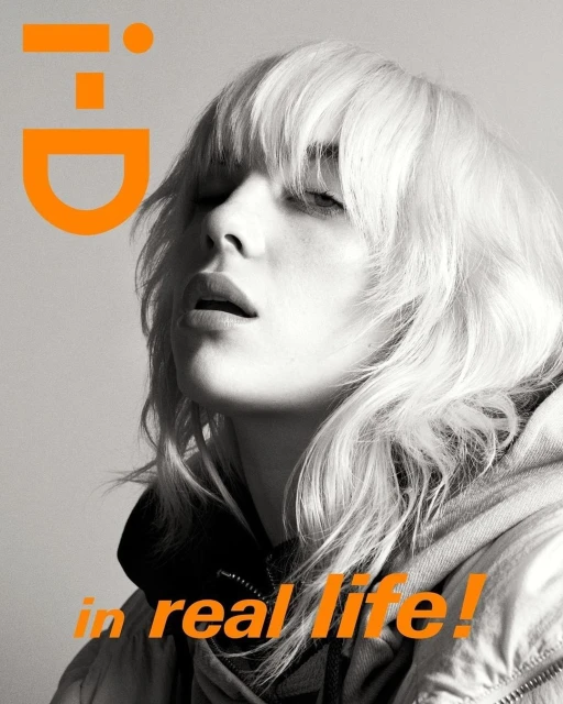 Magazine cover featuring a young adult with platinum blonde hair and a grey hooded sweatshirt, accented by a large orange logo and text.