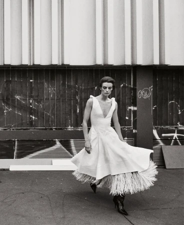 Model in white dress with fringed hem walking outdoors by Glen Luchford