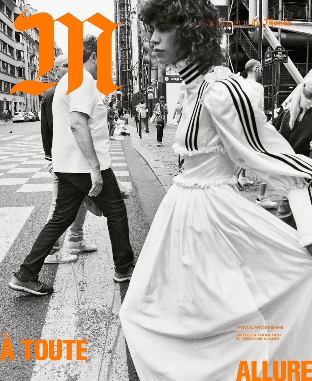 Fashion editorial featuring a model in a white dress on a crosswalk in Paris, with onlookers and large magazine branding.