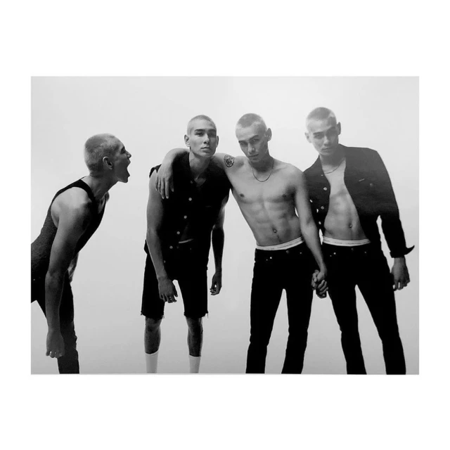Four young adult males pose in a high-contrast black and white photo with a bright backdrop. The composition highlights the subjects.