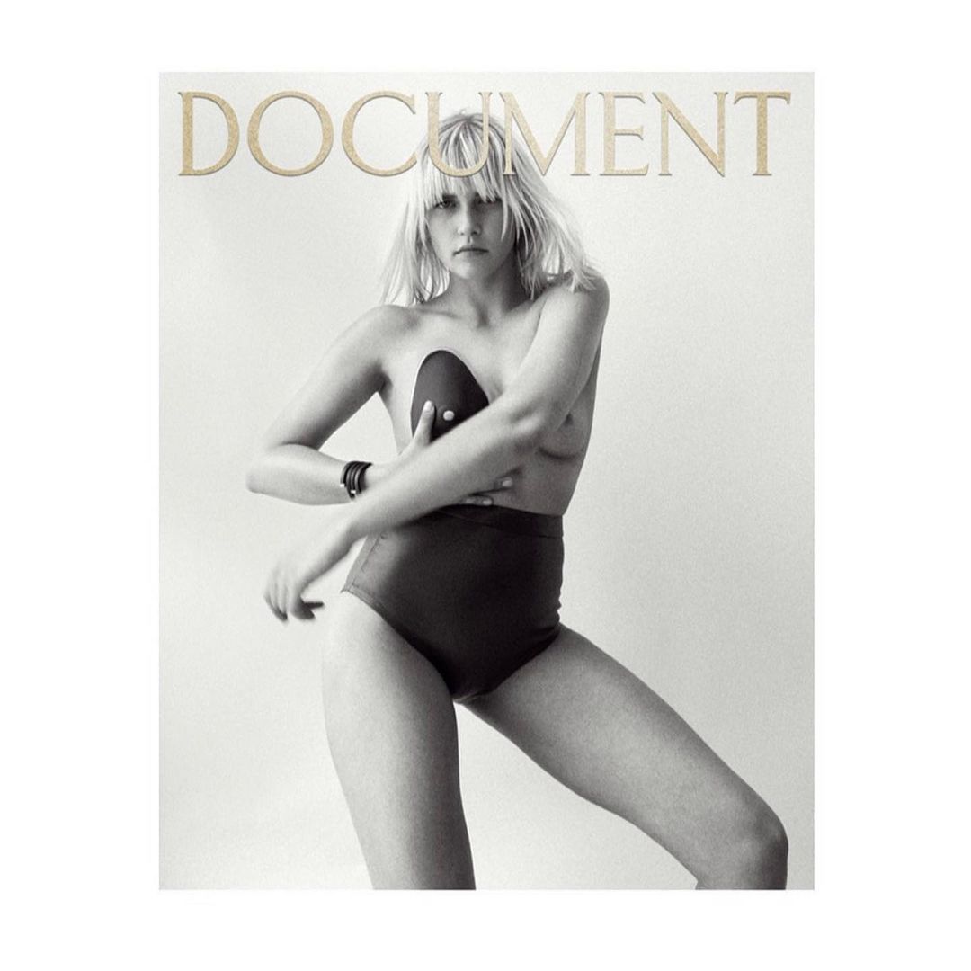 Black and white studio shot of a Caucasian woman posing in high-waisted bottoms, with a black bra, and the word 'DOCUMENT' at the top.