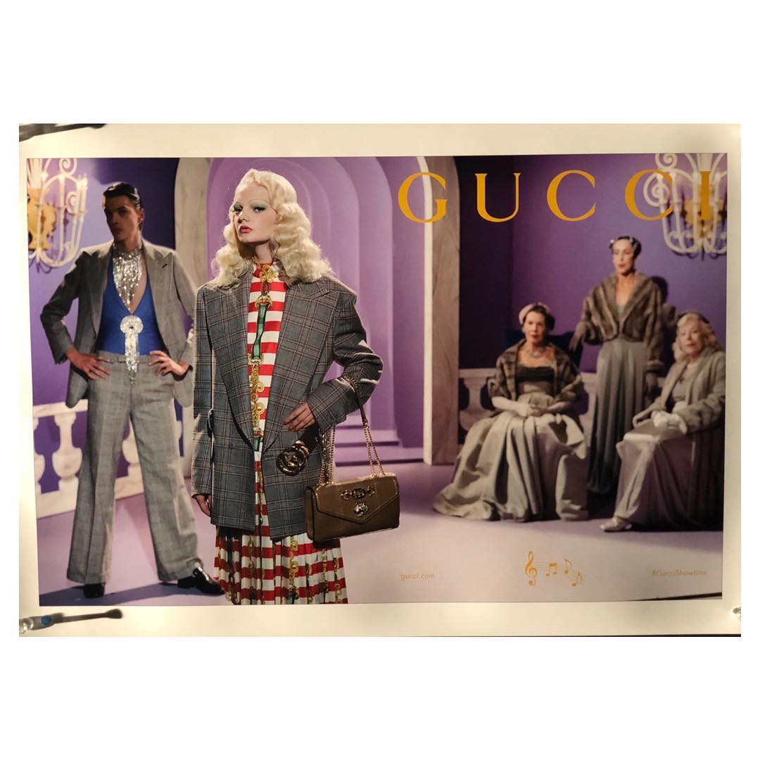 Fashion editorial featuring five women and one man in vintage style clothing, posing against a purple backdrop with Gucci logo.