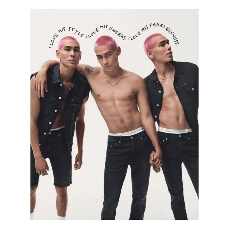 Three figures of a young man with bright pink hair wearing dark denim and holding hands against a neutral white background.