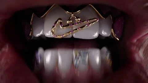 Close-up of teeth with gold and jeweled grills featuring a prominent Nike logo, showcasing dental aesthetics and luxury accessories.
