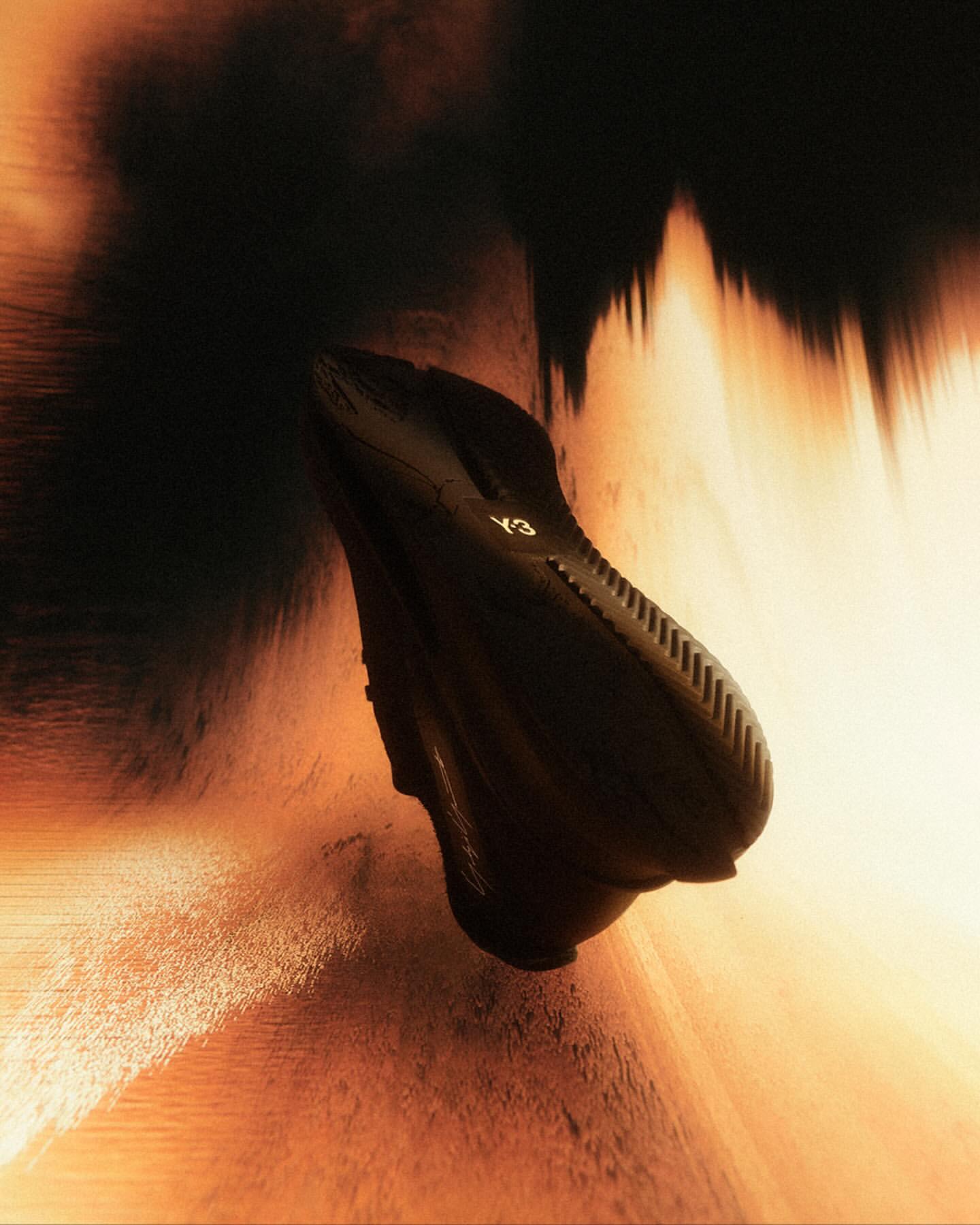 Dramatic product shot of a black Y-3 sneaker. Dynamic lighting and a blurred background add a sense of motion and high fashion.