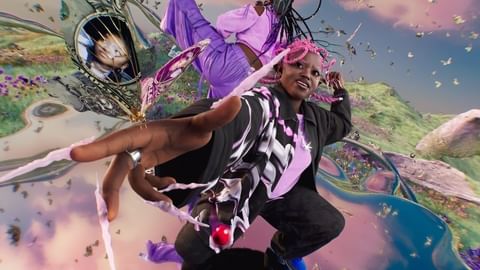 Two adult women pose in front of a digital landscape. One woman is standing and the other one is in the air. 