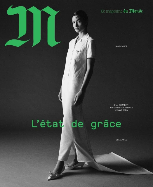 Magazine cover featuring a full-length shot of a slender female model in a white dress with green text and a grey background.