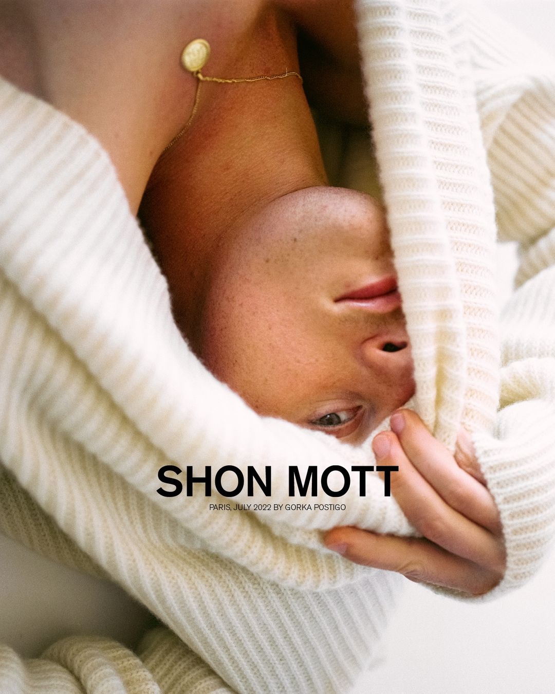 Close-up studio shot of a fair-skinned adult male wearing a knit hoodie, with fair lighting and a gold necklace.