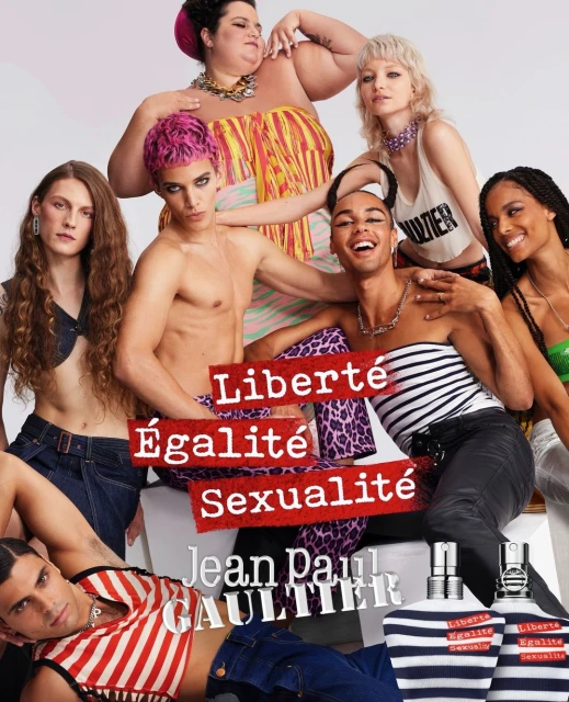 Diverse group of models posing in a studio setting for a Jean Paul Gaultier advertisement, showcasing perfume bottles and bold text.