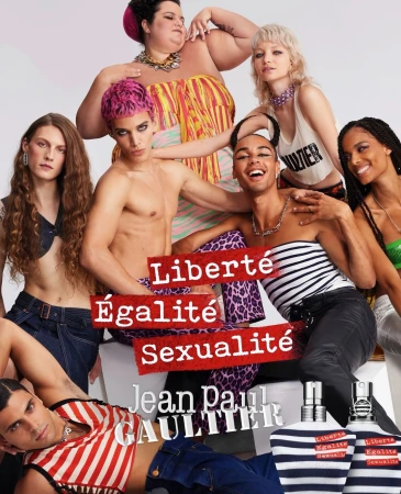Diverse group of models posing in a studio setting for a Jean Paul Gaultier advertisement, showcasing perfume bottles and bold text.