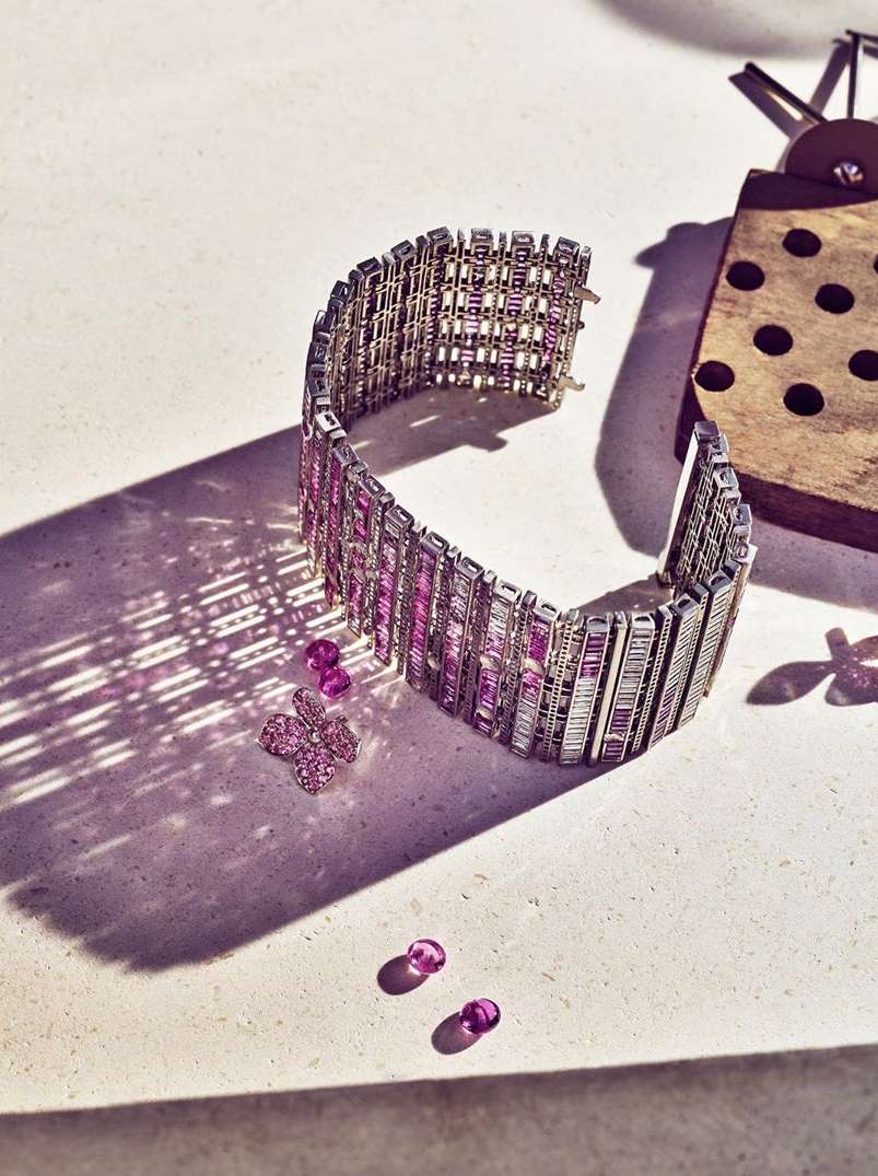 Exquisite bracelet with pink gemstones and white stones, displayed beside jewelry-making tools on a neutral surface.