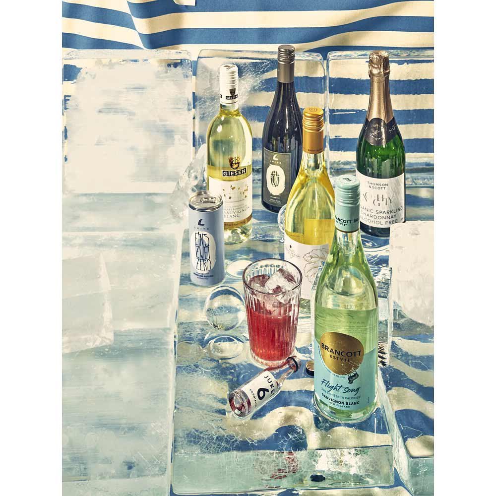 Arrangement of assorted alcoholic beverages on top of ice with a blue and white striped background, suggesting a refreshing and cool presentation.