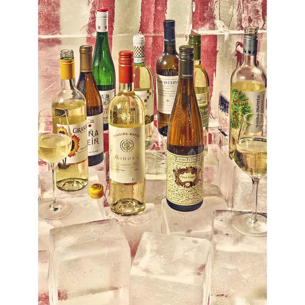 Elegant display of chilled white wine bottles and glasses on ice, perfect for beverage, alcohol, and celebration-themed visuals.
