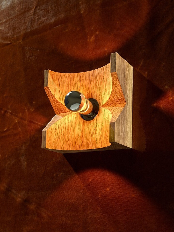 Close-up of a wooden wall sconce with a black knob, set against a mottled brown backdrop, showcasing craftsmanship and design.