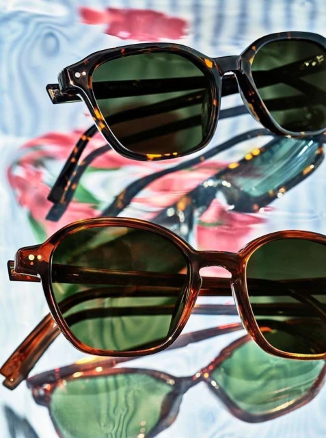 Close-up of two pairs of tortoiseshell sunglasses with green lenses against a softly blurred background. Fashion and style concept.