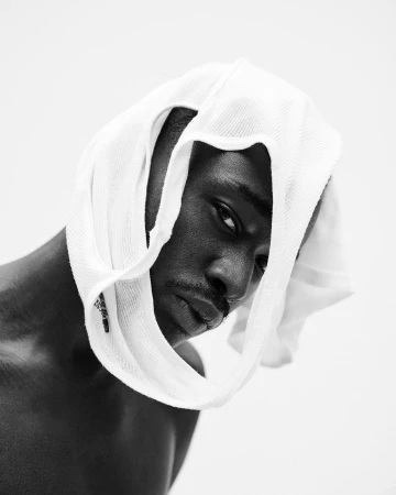 Portrait of a Black man with a white tank top draped over his head by Gray Sorrenti