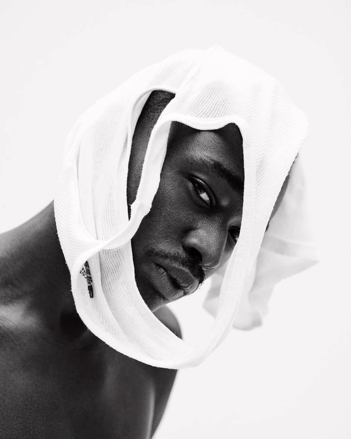 Portrait of a Black man wearing a white tank top wrapped around his head, photographed by Gray Sorrenti.