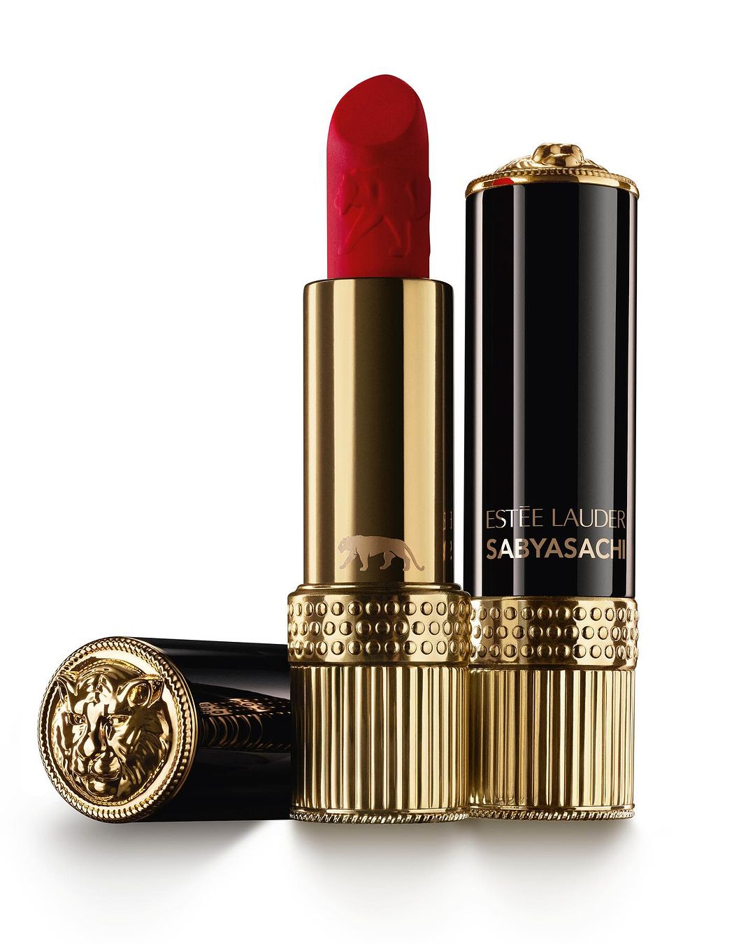 Close-up studio shot of Estee Lauder lipstick in gold and black packaging with an ornate lion design and red lipstick bullet.