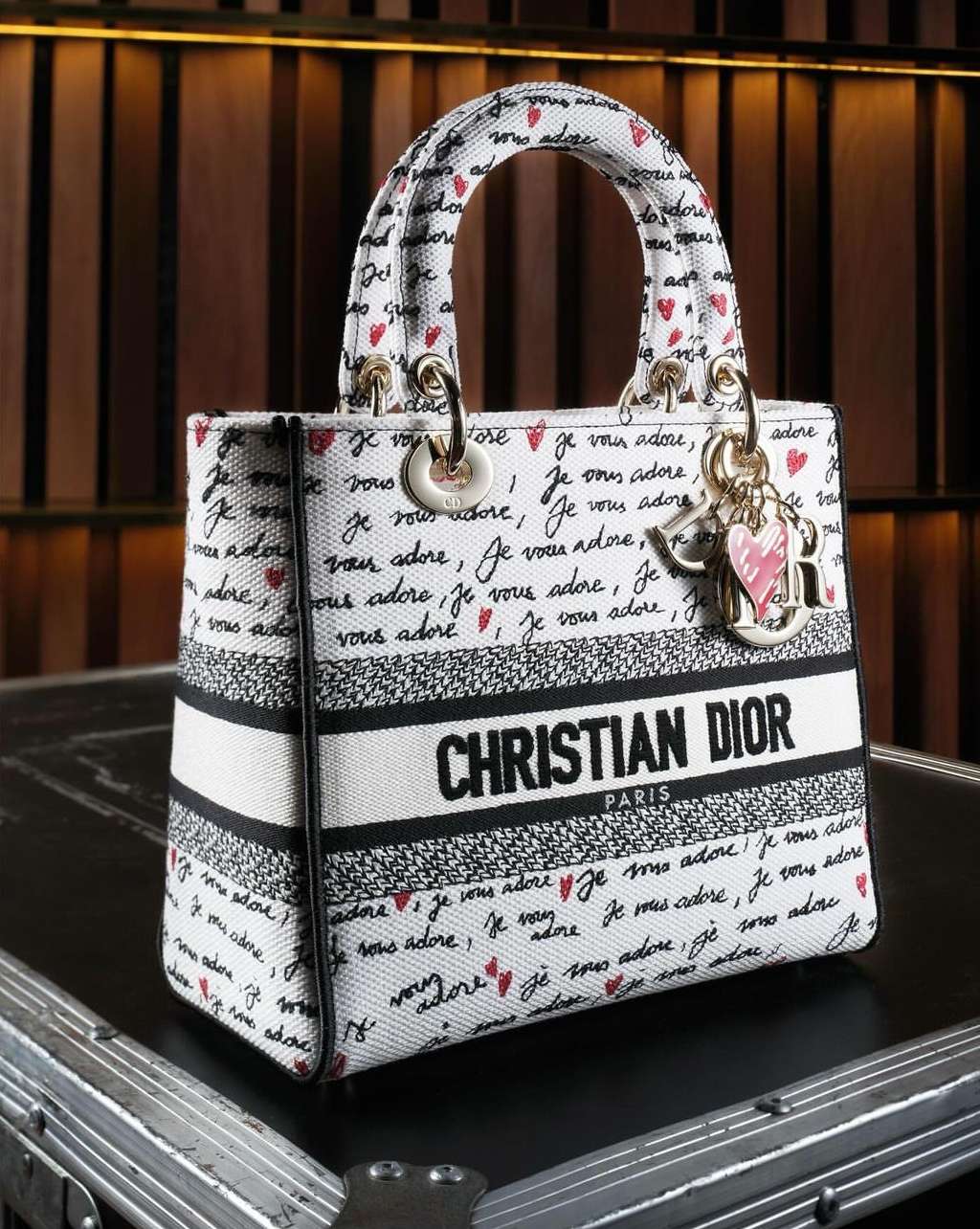 Christian Dior handbag featuring a white canvas exterior printed with black handwriting and red hearts, complemented by gold hardware.
