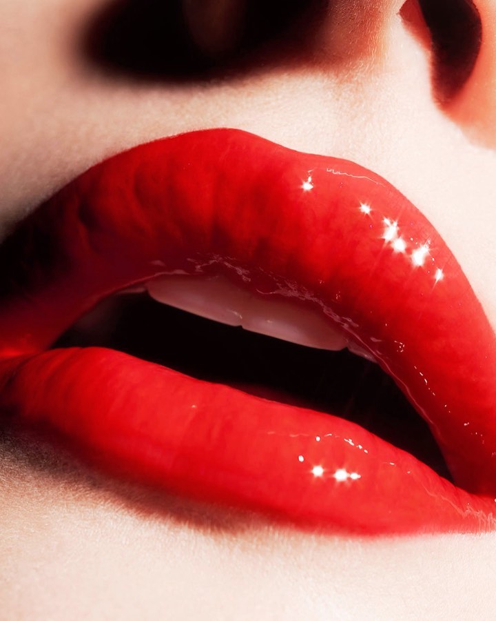 Macro beauty shot of a woman's face featuring luscious red lips with glossy lipstick, accentuated by bright studio lighting and skin texture.