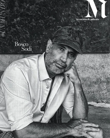Monochrome portrait of a middle-aged man wearing a baseball cap and button-down shirt, resting his chin on his hand.