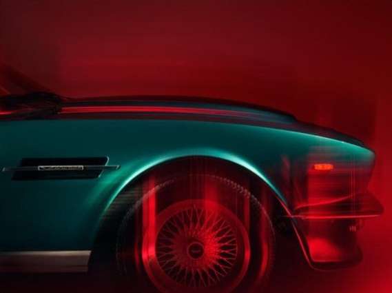 Teal vintage car side profile showing the wheel and front end details with soft red lighting against a red background.