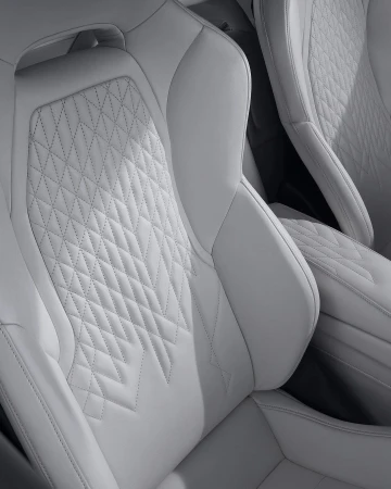 Close-up of white leather car seats featuring diamond stitching and intricate detailing, showcasing automotive interior design.