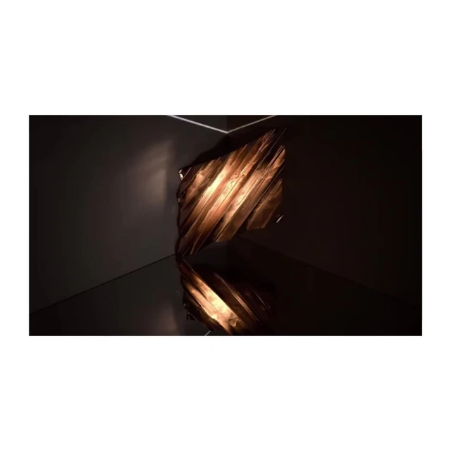 Abstract photograph of a copper-colored, crumpled metallic sculpture reflecting on a dark, glossy surface in a dark corner space.